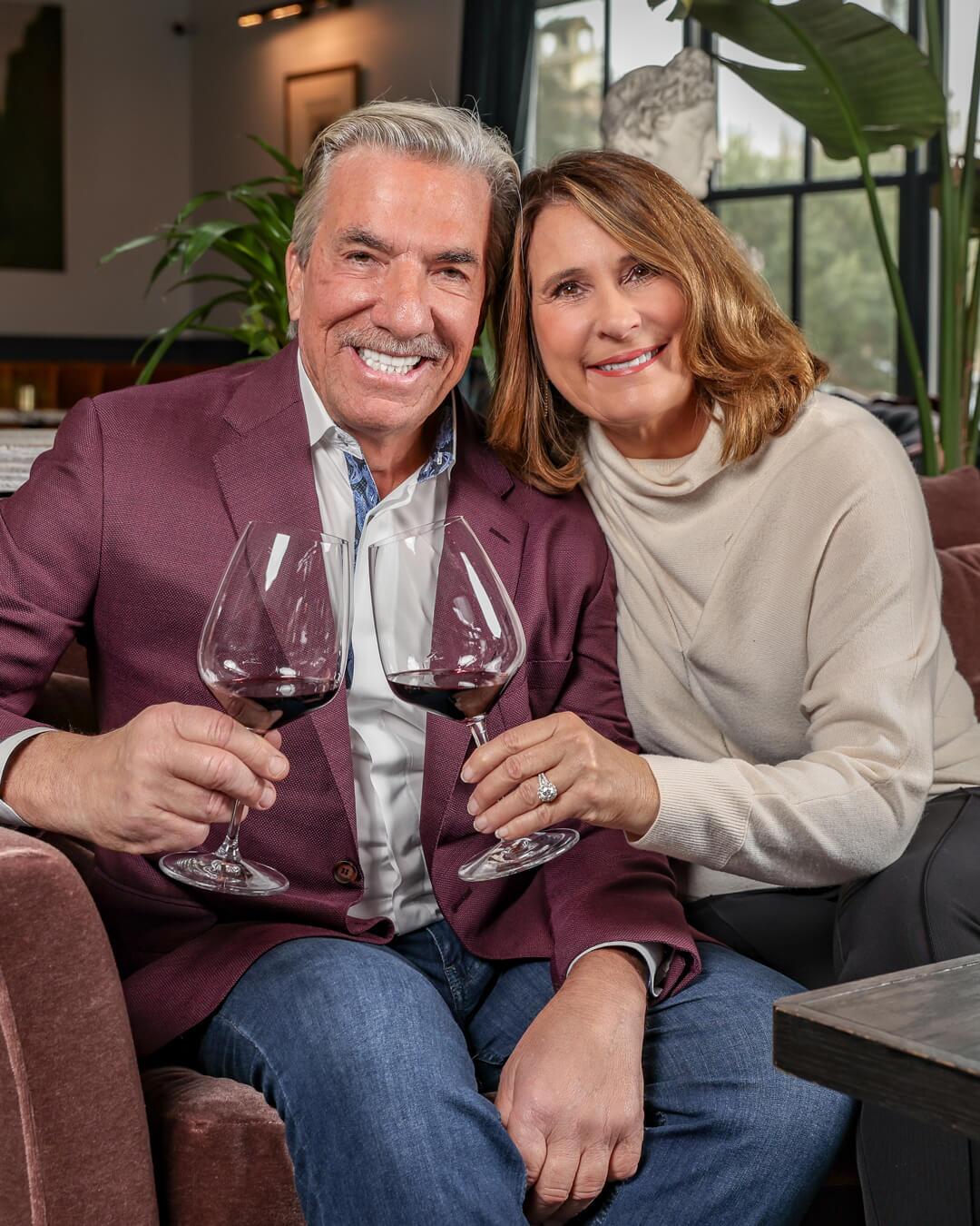 husband and wife smiling holding wine glasses