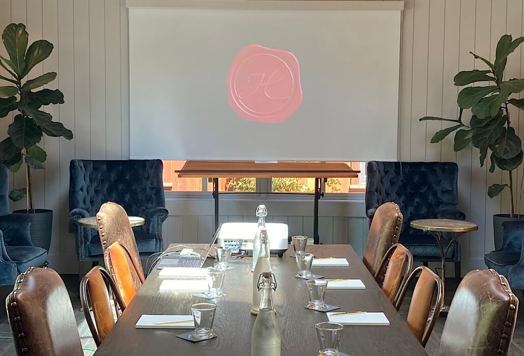 Meeting room with AV screen and projector setup at Handwritten Wines, a refined Napa Valley corporate meeting venue.