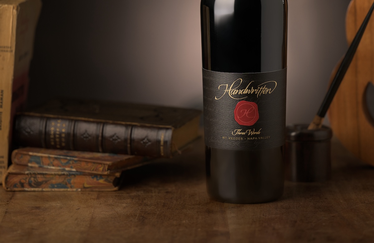 three words wine bottle in front of books on table