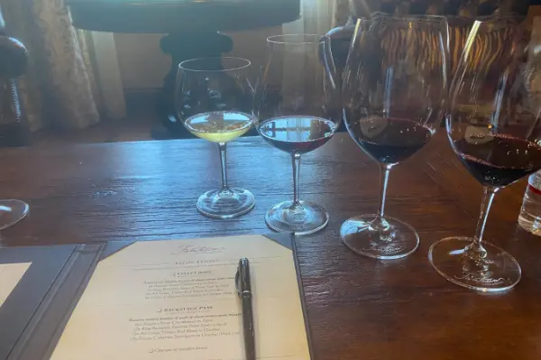 Menu to the left, four glasses lined up on the right on the table.